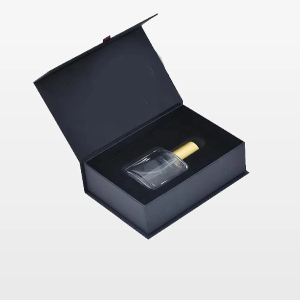 جعبه کتابی تیره و باز با فوم مخمل مشکی و شیشهٔ عطر شفاف با درپوش طلایی